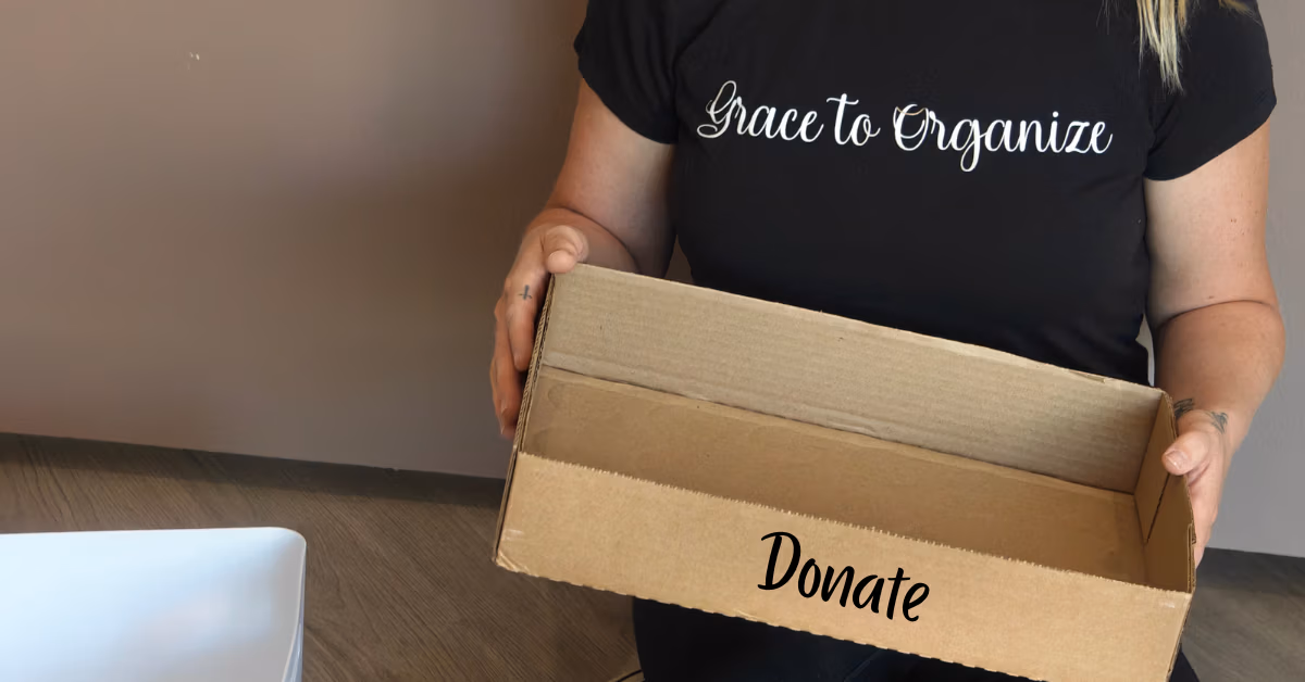 Person holding a box ready for donated items during a decluttering session.